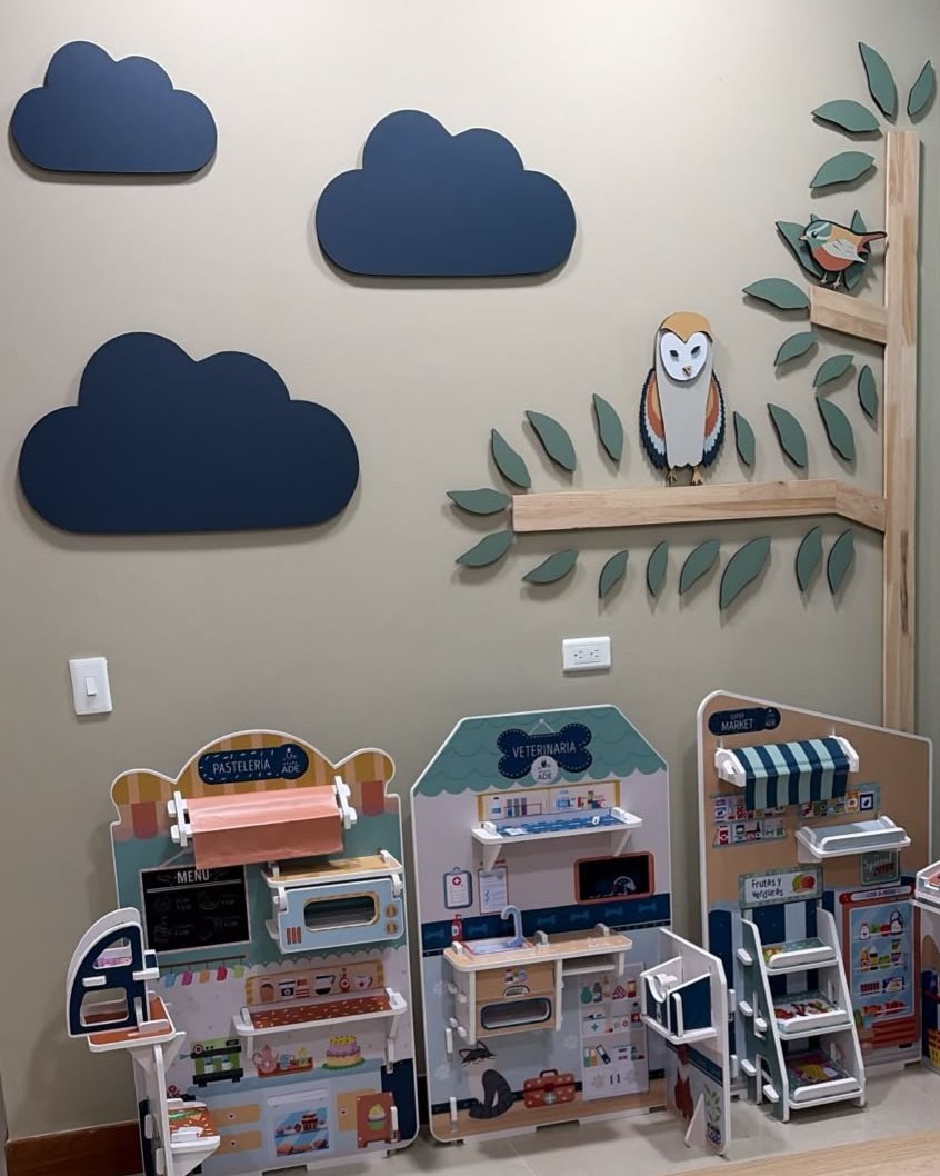 Espacio de juego de NeuroADE: mural del búho y el pajarito, estaciones temáticas y material sensorial